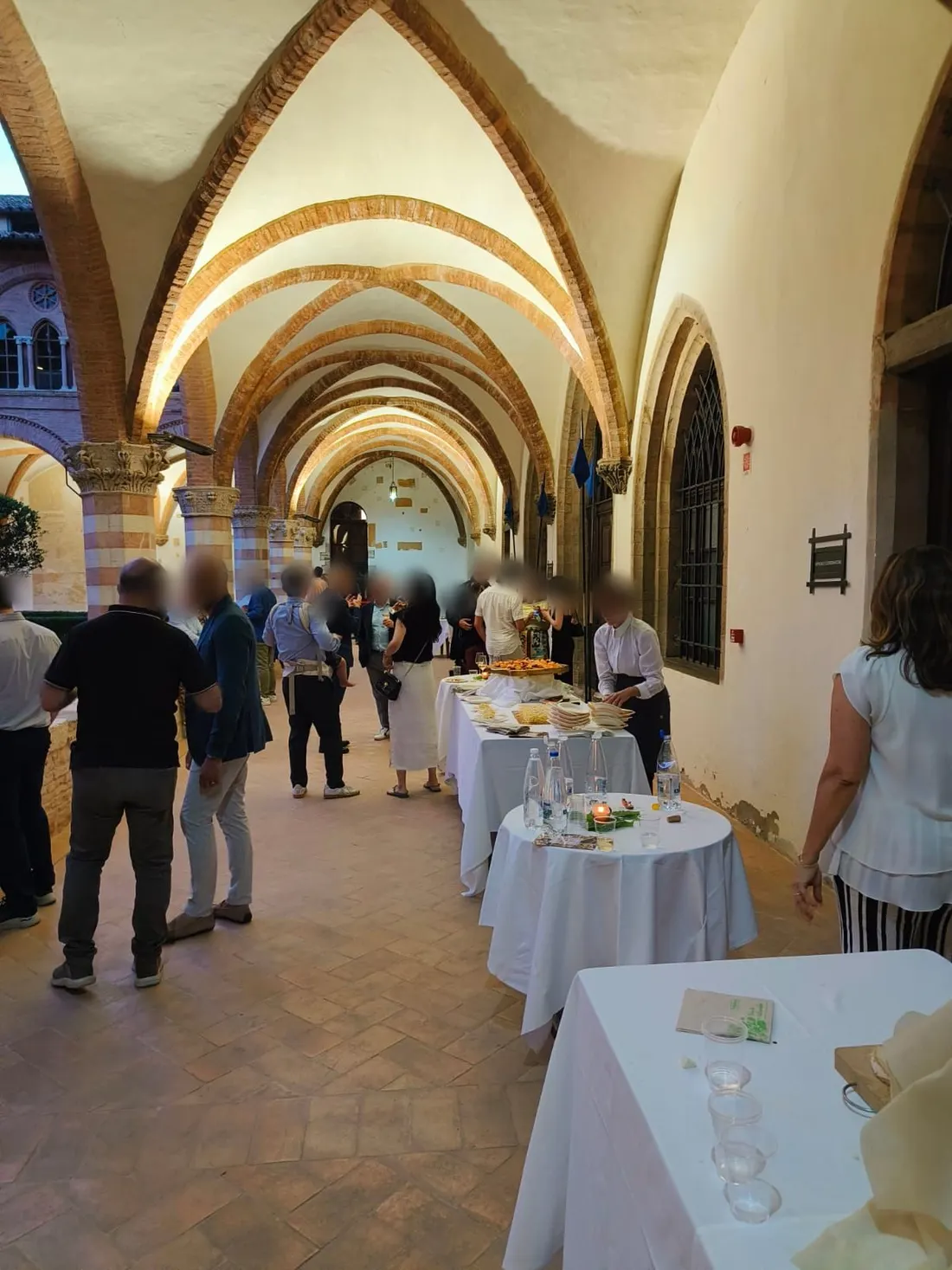 Buffet allestito sotto il loggiato a volte di un chiostro storico nel centro di Perugia